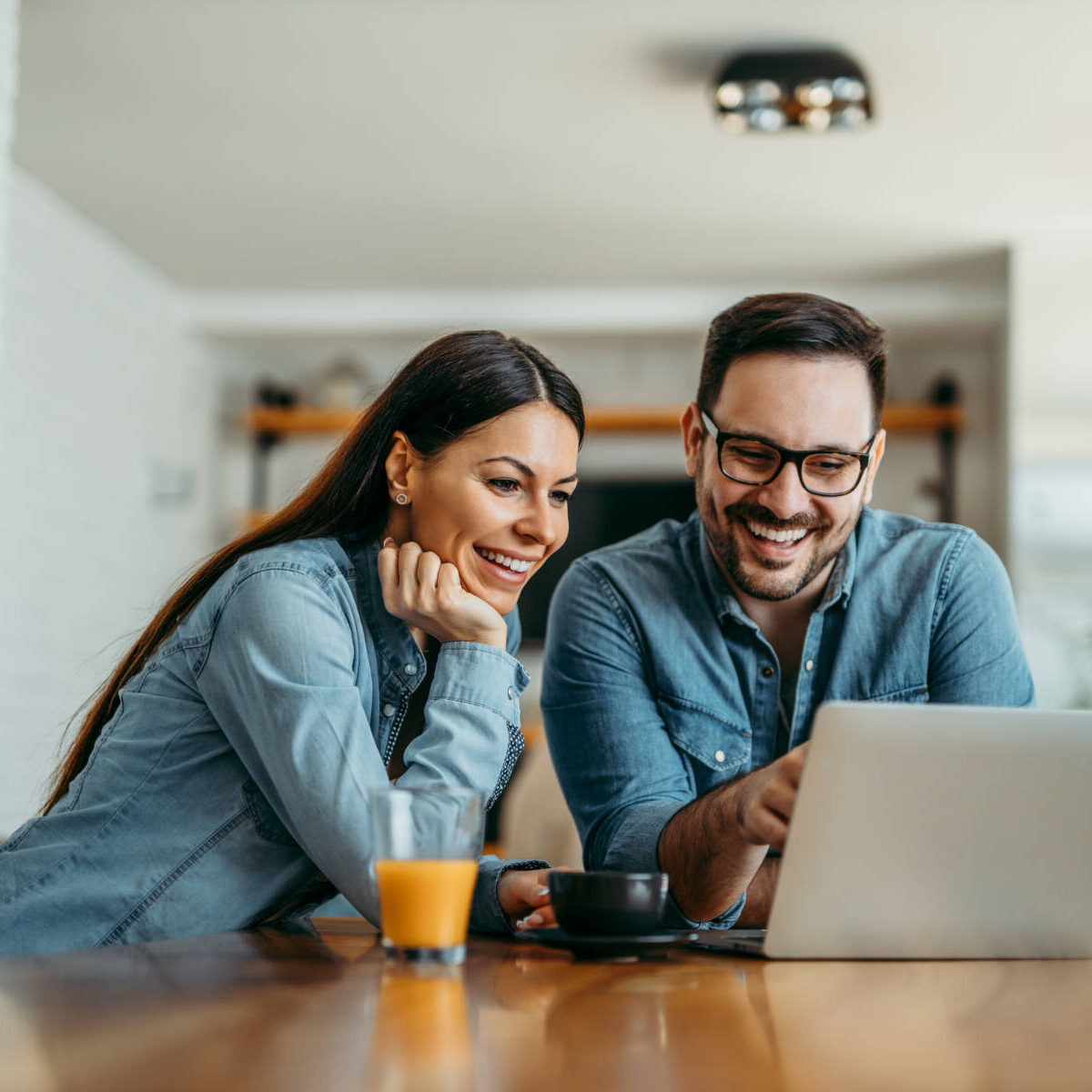 Portrait of a cute smiling couple looking at laptop together at home.