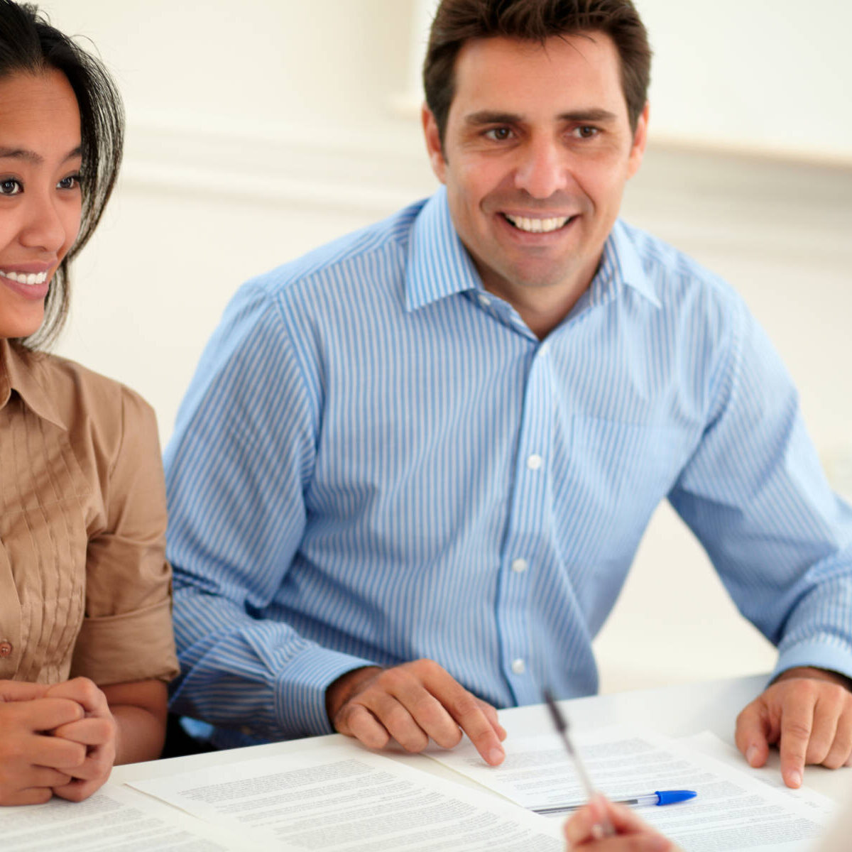 Portrait of young woman and man interested in a contract sitting and smiling on office desk