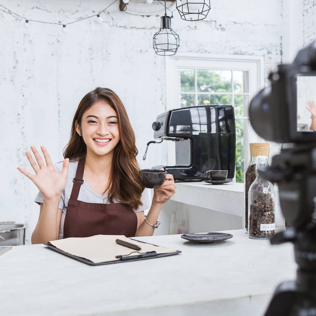 Startup successful small business owner sme beauty girl video online marketing with camera in cafe. Portrait of young asian tan woman barista cafe owner. SME entrepreneur business concept